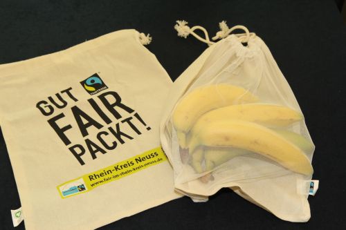 Ein Jute-Beutel mit dem Aufdruck 'Gut. Fairtrade packt an.' und ein Obstnetz mit Bananen