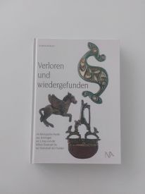 Ein geschlossenes Buch auf einem Tisch, mit einem einfachen Cover-Design. Der Titel "Verloren und wiedergefunden" ist deutlich sichtbar und das Buch scheint in gutem Zustand zu sein, bereit zum Lesen oder zur Aufbewahrung in einer Bibliothek.